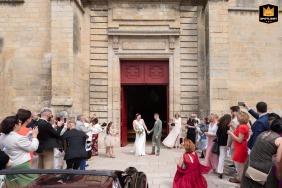 A bride and groom exit the Church of Gouvieux in France. The image shows the couple walking after their ceremony.